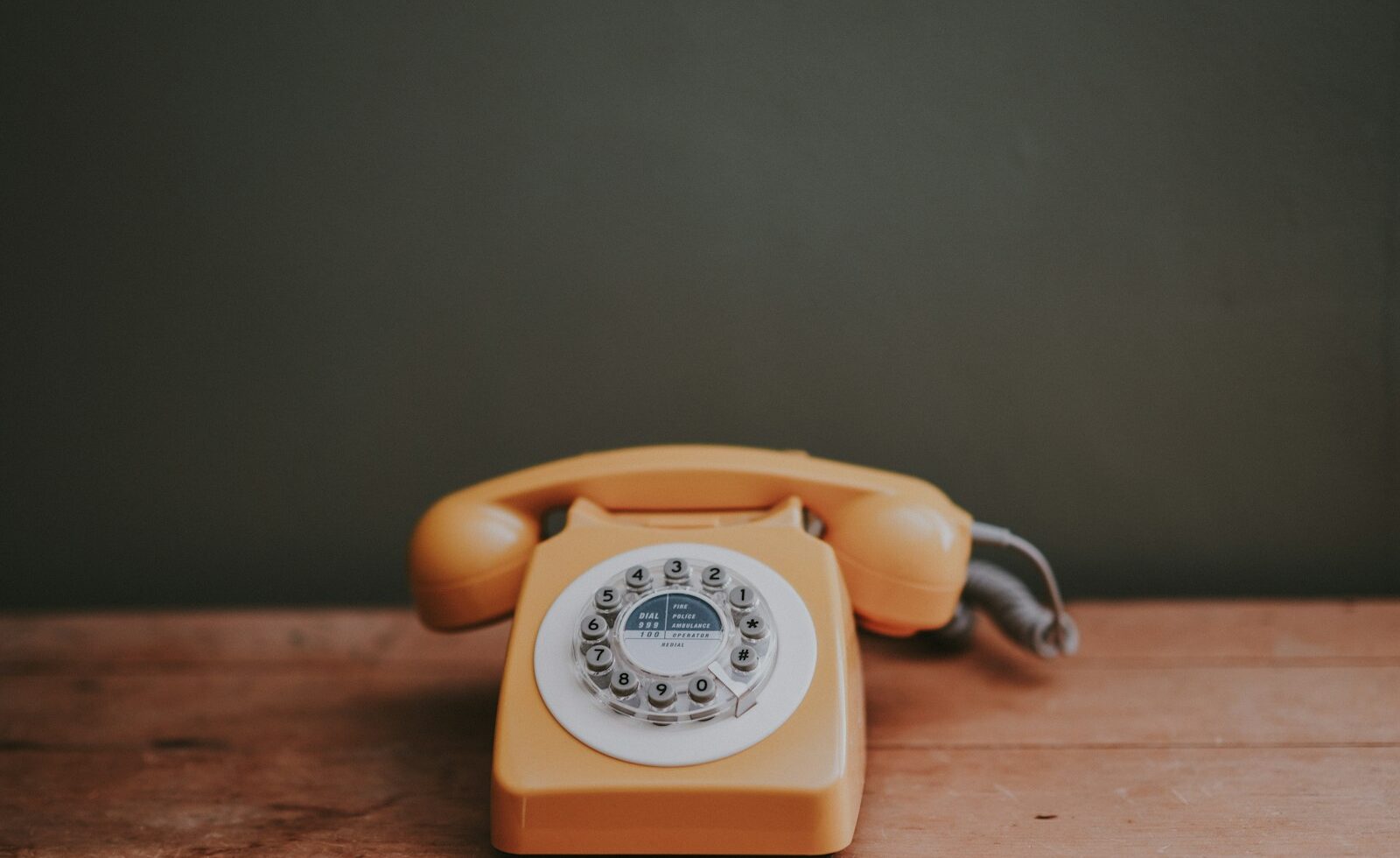 brown rotary dial telephone in gray painted room