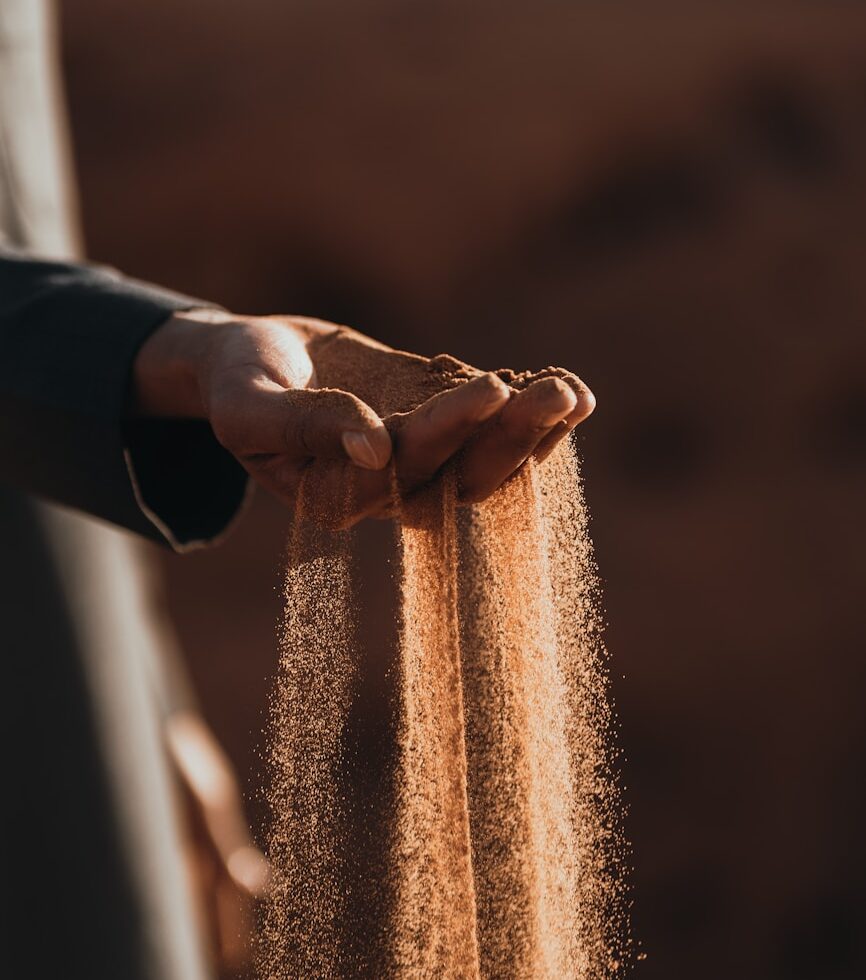 a person holding sand in their hands